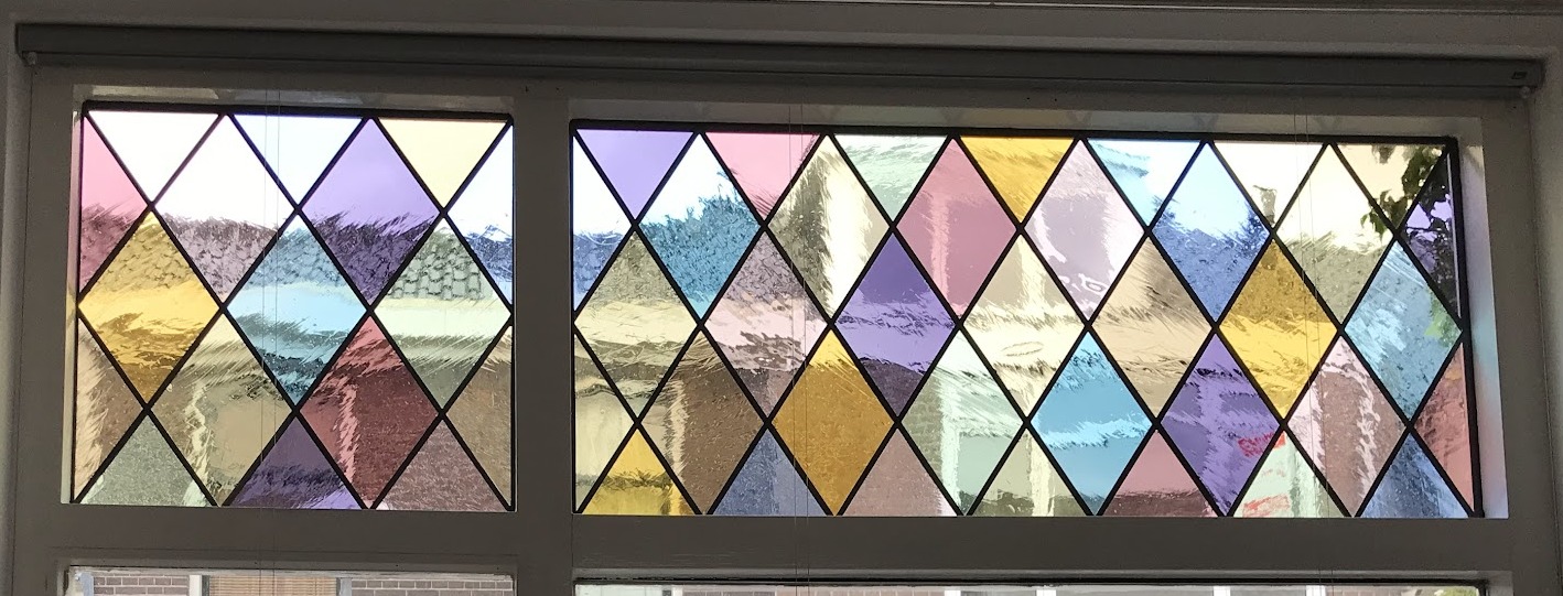 Bovenlicht met ruitmotief in roze, geel, paars en lichtblauw glas